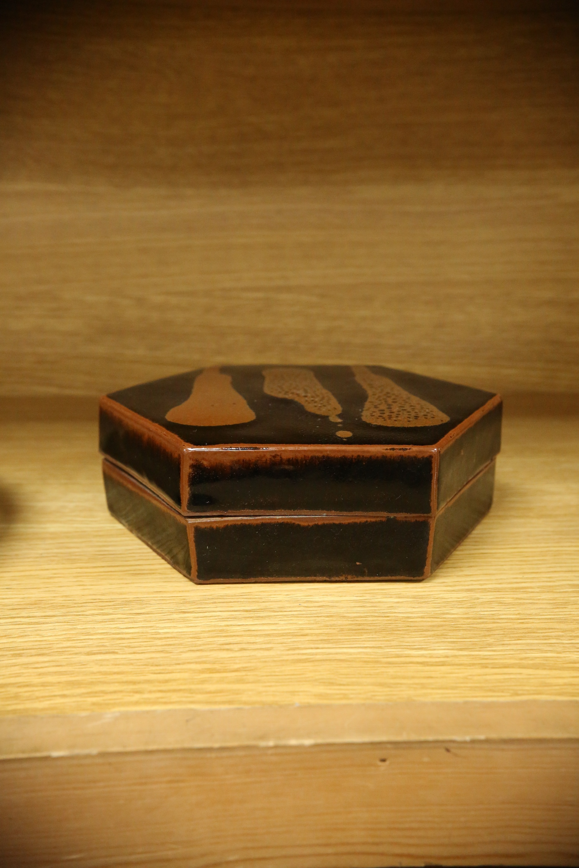 A Japanese studio tenmoku glazed hexagonal box and cover, unmarked, 18cm wide. Condition - good